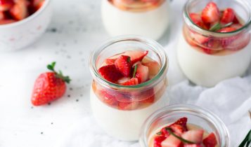 sliced strawberries in clear glass jar with cream