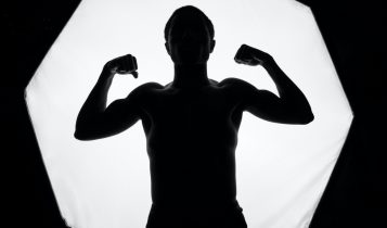 topless man holding black and white ceramic mug